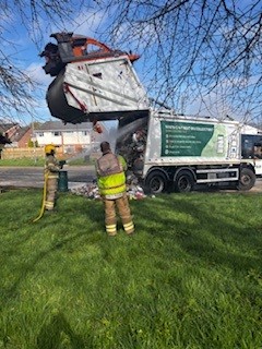 Firefighters extinguishing a bin lorry fire